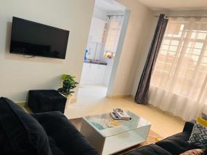 a living room with a black couch and a tv at Adjana’s Cozy apartment in Nairobi