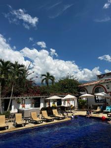 uma piscina de resort com espreguiçadeiras e guarda-sóis em Hotel Villa María Santa Fe de Antioquia em Santa Fe de Antioquia