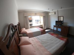 a hotel room with two beds and a television at Suite 5 Estrellas in Santa Cruz de la Sierra