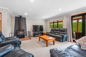 a living room with leather furniture and a fireplace at Hāwea Delight - Lake Hāwea Holiday Home in Lake Hāwea