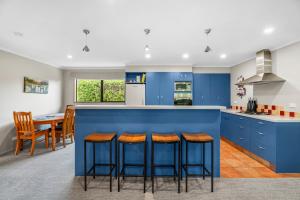 a kitchen with blue cabinets and bar stools at Hāwea Delight - Lake Hāwea Holiday Home in Lake Hāwea
