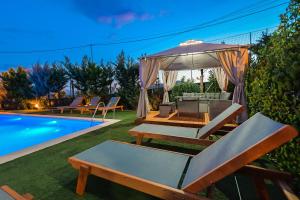 einen Hinterhof mit einem Pool mit Stühlen und einem Sonnenschirm in der Unterkunft Villa Vrion in Sarandë