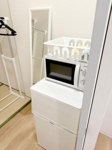 a microwave oven sitting on top of a white refrigerator at 道頓堀House in Osaka
