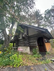 una piccola casa con un tendone nero accanto a un albero di しぇろくまサウナ＆カフェ a Shinano