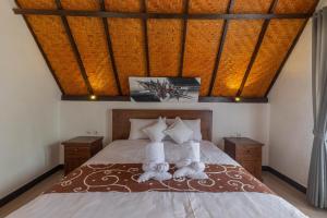 Maskot Penida Cottage في نوسا بينيدا: غرفة نوم مع اثنين من الحيوانات المحشوة على سرير