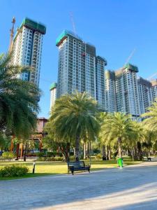 a park with palm trees and a bench in front of tall buildings at The Origami: Exclusive Living ! in Long Bình