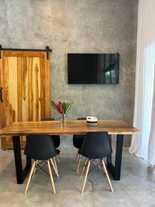 uma mesa de madeira com cadeiras e uma televisão na parede em Munay House em Santa Teresa