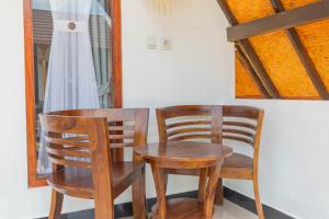 ペニダ島にあるMaskot Penida Cottageの窓のある客室で、椅子2脚とテーブル1台が備わります。