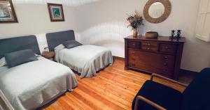 a bedroom with two beds and a dresser and a mirror at La Casa de María Pita in A Coruña