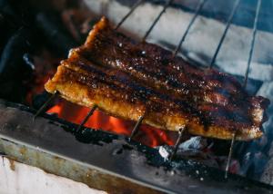 Ein Stück Fleisch kocht auf einem Grill in der Unterkunft 福田屋 in Imazu