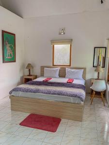 a bedroom with a large bed with two red pillows at Carla Garden Villa in Yogyakarta