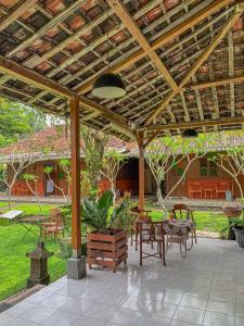 a patio with tables and chairs under a wooden pergola at Carla Garden Villa in Yogyakarta