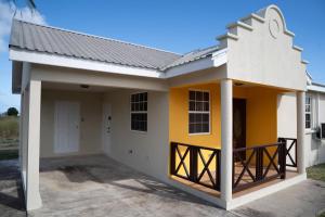 uma casa com uma fachada amarela e branca em Sunset Cove Barbados em Christ Church