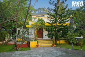 Casa amarilla y blanca con puerta amarilla en Eden's Estate by StayVista - Featuring cozy rooms with a private pool, and modern interiors for a delightful stay, en Alibaug