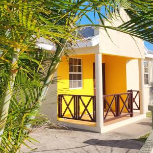 Casa blanca y amarilla con porche en Sunset Cove Barbados, en Christ Church