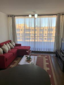 uma sala de estar com um sofá vermelho e uma grande janela em Departamento LA FLORIDA em Santiago