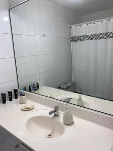 uma casa de banho com um lavatório e um espelho grande em Departamento LA FLORIDA em Santiago