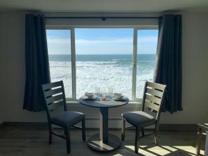 uma mesa e cadeiras em frente a uma janela com o oceano em West Beach Suites em Lincoln City