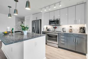 una cocina con armarios blancos y electrodomésticos de acero inoxidable en Waterfront Two Bedroom apartment in a brand new building apts, en Washington