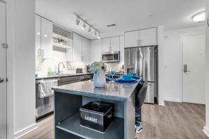Two Bedroom Fully Furnished Apartment near Waterfront apts في واشنطن: مطبخ بدولاب بيضاء وجزيرة عليها مزهرية