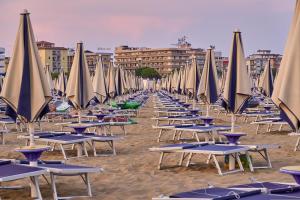 - une rangée de chaises et de parasols sur une plage dans l'établissement Colourful seaside flat with pool on the rooftop, à Bibione