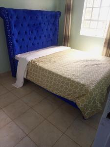 a bed with a blue headboard in a room at Verona Apartments in Thika