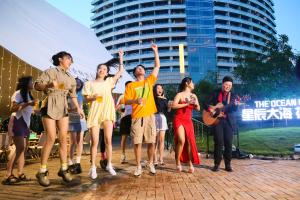 Un groupe de personnes debout sur un trottoir avec les mains en l'air dans l'établissement Shangri-La Qinhuangdao, à Qinhuangdao