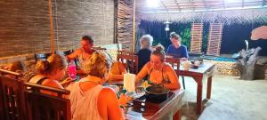 een groep mensen die aan tafel zitten in een restaurant bij River View Safari Cottage. in Udawalawe