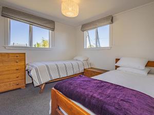 a bedroom with two beds and a dresser and two windows at Alpine Rest - National Park Holiday Home in National Park
