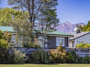 a house with a fence and mountains in the background at Alpine Rest - National Park Holiday Home in National Park