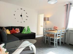 a living room with a couch and a table with a clock at The Blossom - Largs in Largs