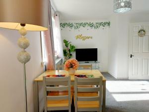 a dining room with a table and chairs and a television at The Blossom - Largs in Largs