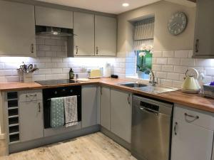 a kitchen with white cabinets and stainless steel appliances at The Hut- Private 1 Bed Guesthouse in Lymington Town Centre, garden & parking in Lymington