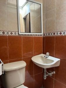 y baño con lavabo, aseo y espejo. en Hotel Villa Sofia, en Villavicencio