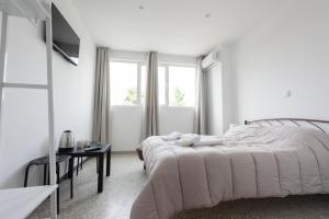 1 dormitorio blanco con 2 camas y mesa en Liberal Gazi en Athens