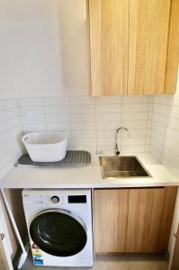 a kitchen with a sink and a washing machine at Hamilton By the Bay 3 Newly Built in Safety Beach