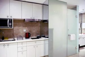 a kitchen with white cabinets and a microwave at Modena by Fraser Changsha in Changsha