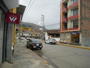 twee auto's rijden door een straat met gebouwen bij Wayra Hotel in Huaraz