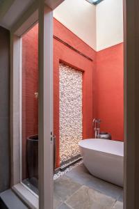 a bathroom with a tub and a red wall at Taj Sawai,Ranthambore in Sawāi Mādhopur