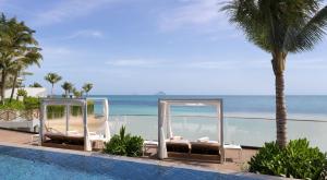 uma piscina com duas cadeiras junto ao oceano em Gran Meliá Nha Trang em Nha Trang