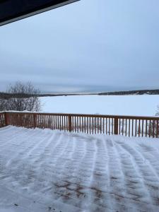 a snow covered deck with a fence and a body of water at Top floor lakefront condo with Mountain Views! in Wasilla