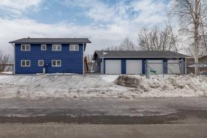 una casa blu nella neve di fronte di Top floor lakefront condo with Mountain Views! a Wasilla