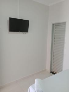 Camera bianca con letto e televisione a parete di Hotel Califórnia a Barreiras
