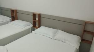 2 letti in una camera con lenzuola bianche di Hotel Califórnia a Barreiras