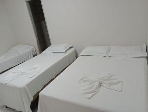 2 letti con lenzuola bianche e un arco sopra di Hotel Califórnia a Barreiras