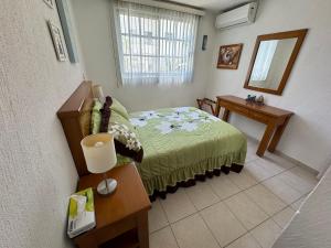 een slaapkamer met een bed, een tafel en een spiegel bij Acapulco diamante departamento con playa ecológico in Acapulco
