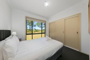 um quarto com uma cama branca e uma janela em Potters Apartments em Cessnock