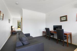 a living room with a couch and a desk at Potters Apartments in Cessnock
