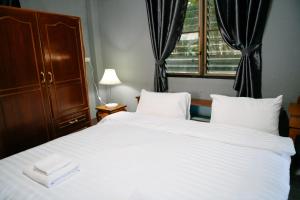 a bedroom with a large white bed and a window at Nadee House in Ban Pa Sang (1)