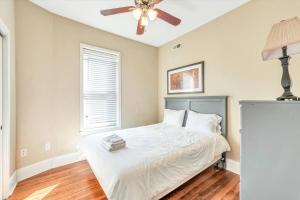 een slaapkamer met een wit bed en een plafondventilator bij St Louis Townhome Perfect for Groups in Tower Grove